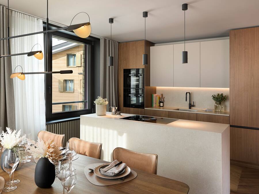 A modern kitchen with a central island, a dining area with a table set for two, and a large window with curtains.