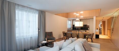 A modern hotel room with a living area, dining space, and a kitchen.