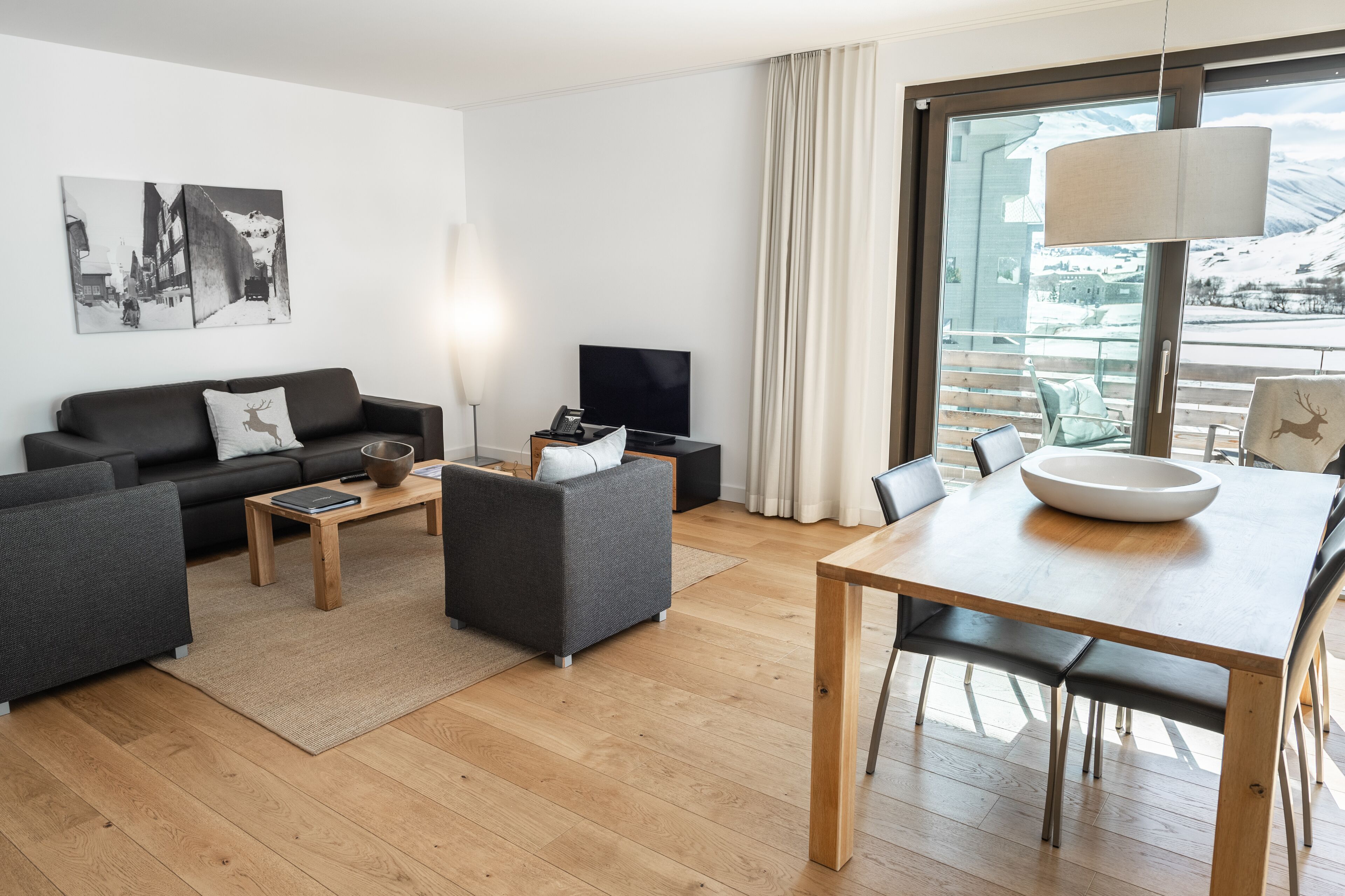 En moderne stue med sofa, sofabord, tv og spisebord med stole.