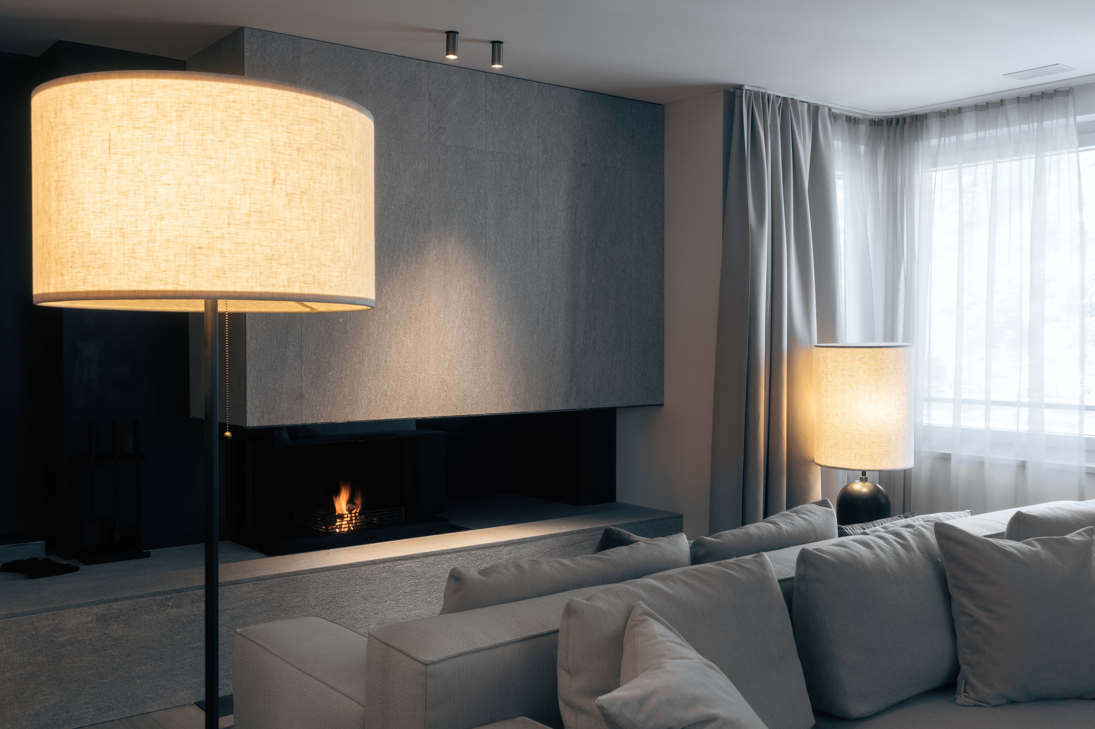 A modern living room with a fireplace, a large floor lamp, and a sofa.