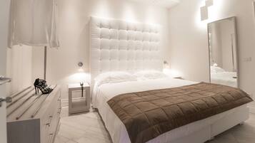 Un dormitorio moderno con una cama grande, una mesita de noche, un espejo y un perchero.