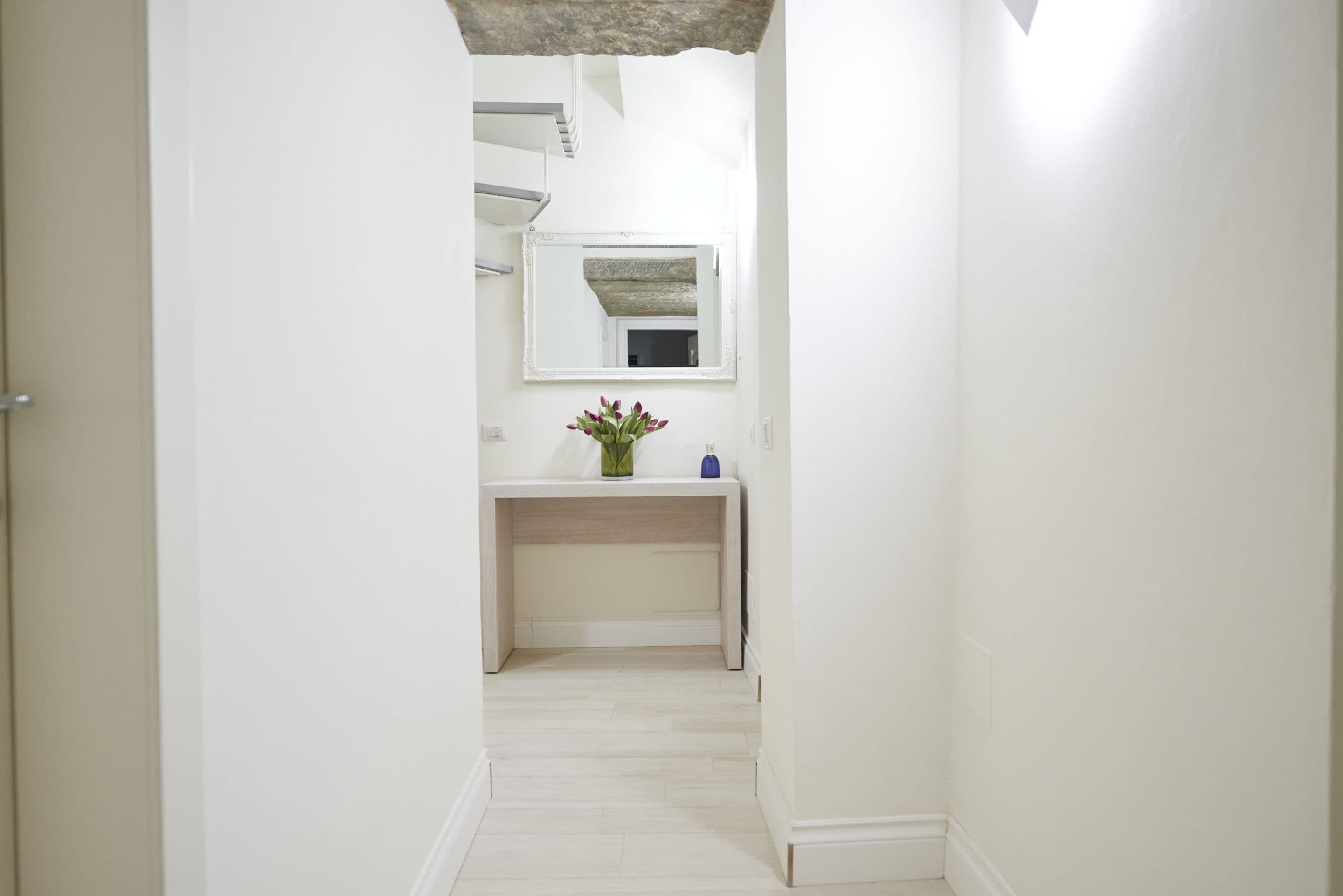 A narrow hallway with a white vanity and a mirror above it.