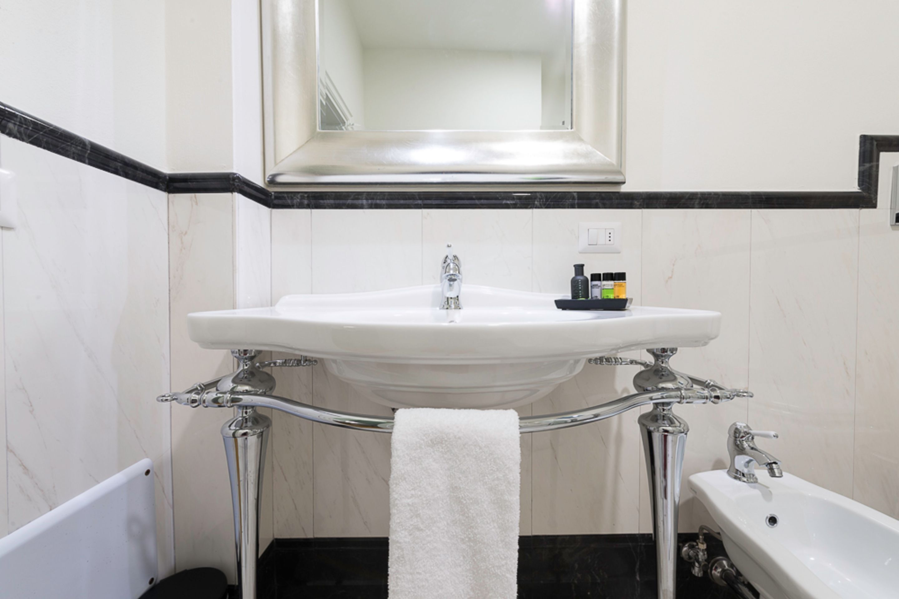 A bathroom with a white sink, a mirror above it, and a towel hanging on a rack.