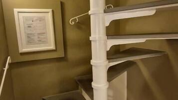 Una escalera en espiral con barandillas blancas y un certificado enmarcado en la pared.