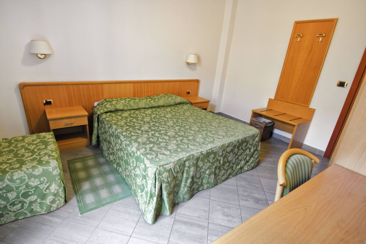 A bedroom with a bed, bedside tables, a chair, a desk, and a wardrobe.