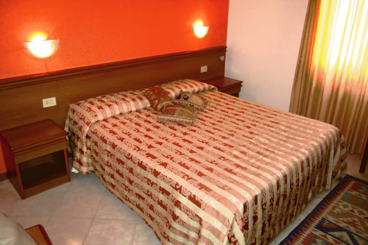 A hotel room with a bed, nightstands, and a night lamp.