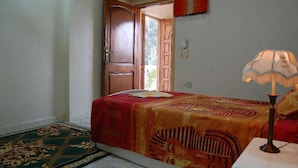 Quarto com cama, luminária, porta e tapete.