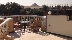 Um terraço com mesa e cadeiras, uma escadaria e vista para montanhas.