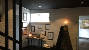 A dimly lit room with a brick wall, a table with framed certificates, a small window, and a display board. - Malling Kro (Malling)