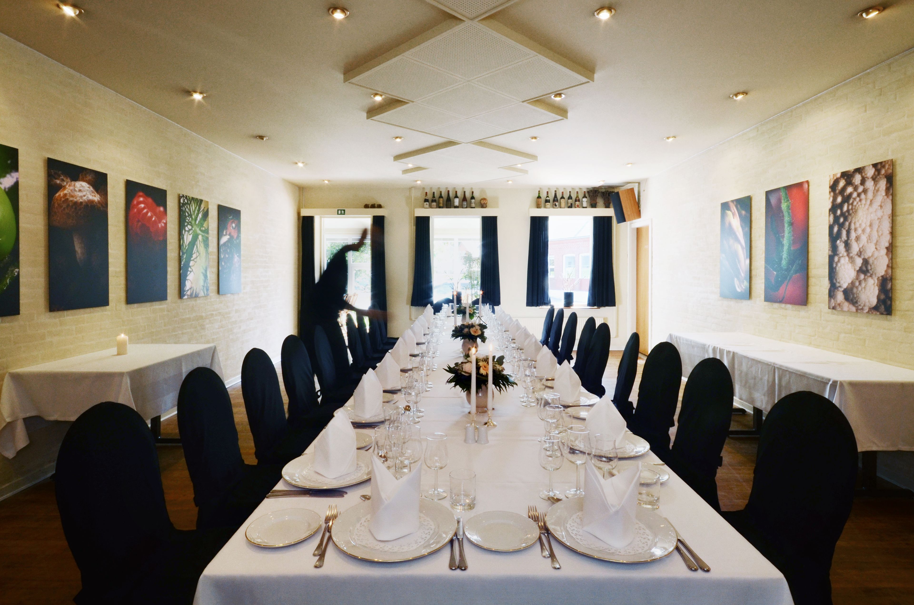 A long dining table set for a formal event with chairs, plates, and glasses.
