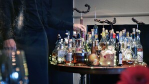 A bar area with various bottles of alcohol and a person standing by the bar. - Malling Kro (Malling)