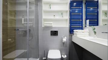 Un baño moderno con ducha envuelta en vidrio, inodoro blanco y zona de lavamanos con sujetabroches azules.