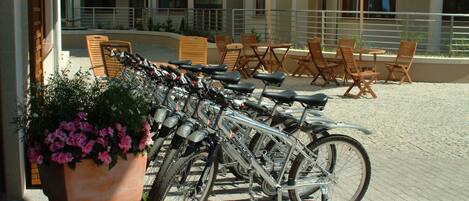 A patio area with bicycles parked, outdoor seating, and a planter with flowers.