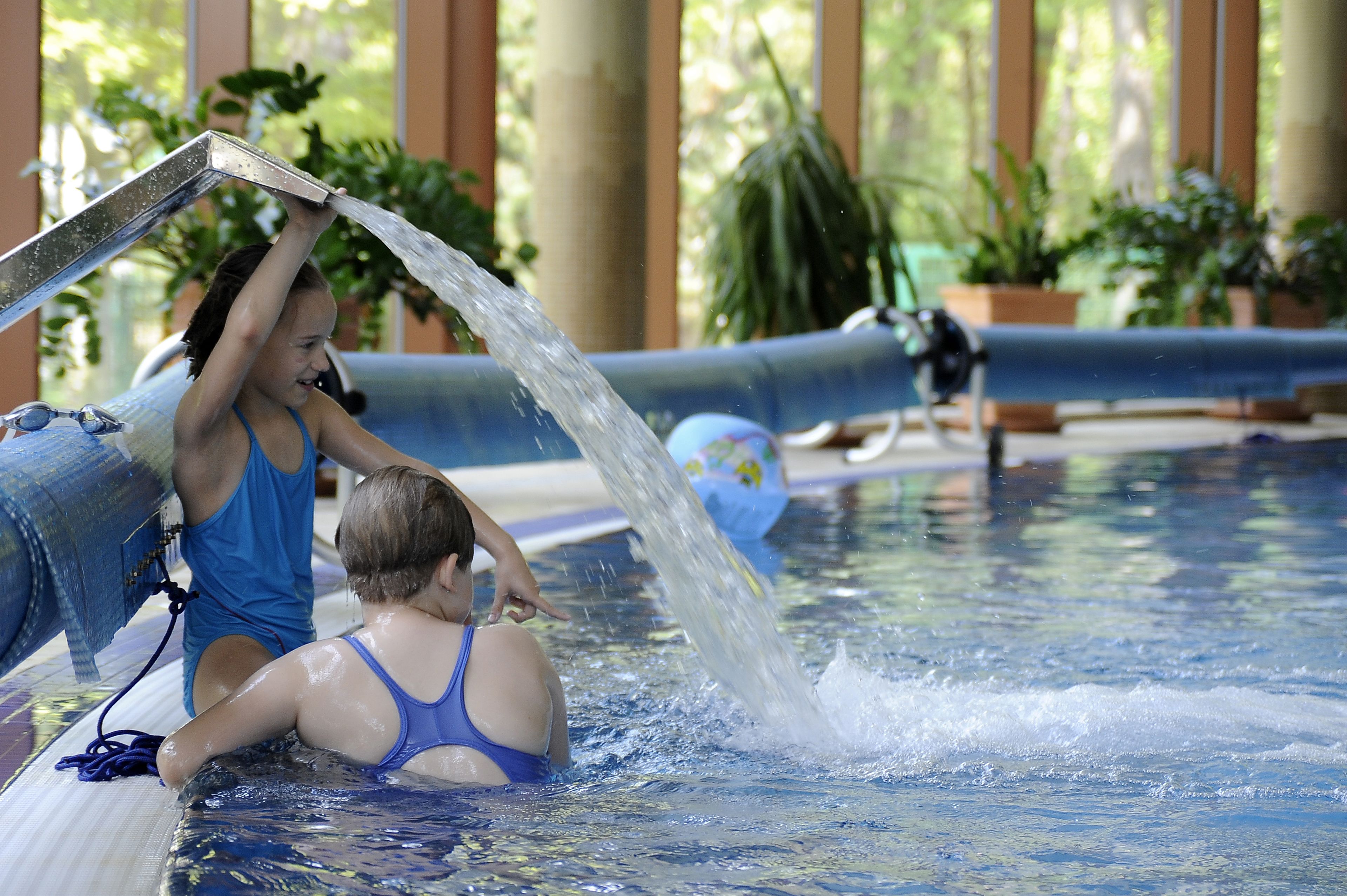 Ein Poolbereich mit Wasserspiel und einer Person in einem blauen Badeanzug.