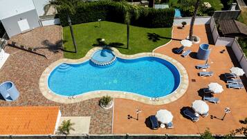 Una piscina al aire libre de temporada, sombrillas, tumbonas