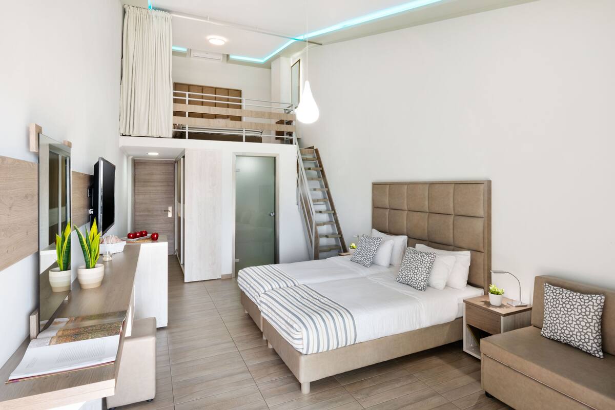 Une chambre moderne avec un lit en mezzanine, un bureau et une table de chevet avec une lampe.
