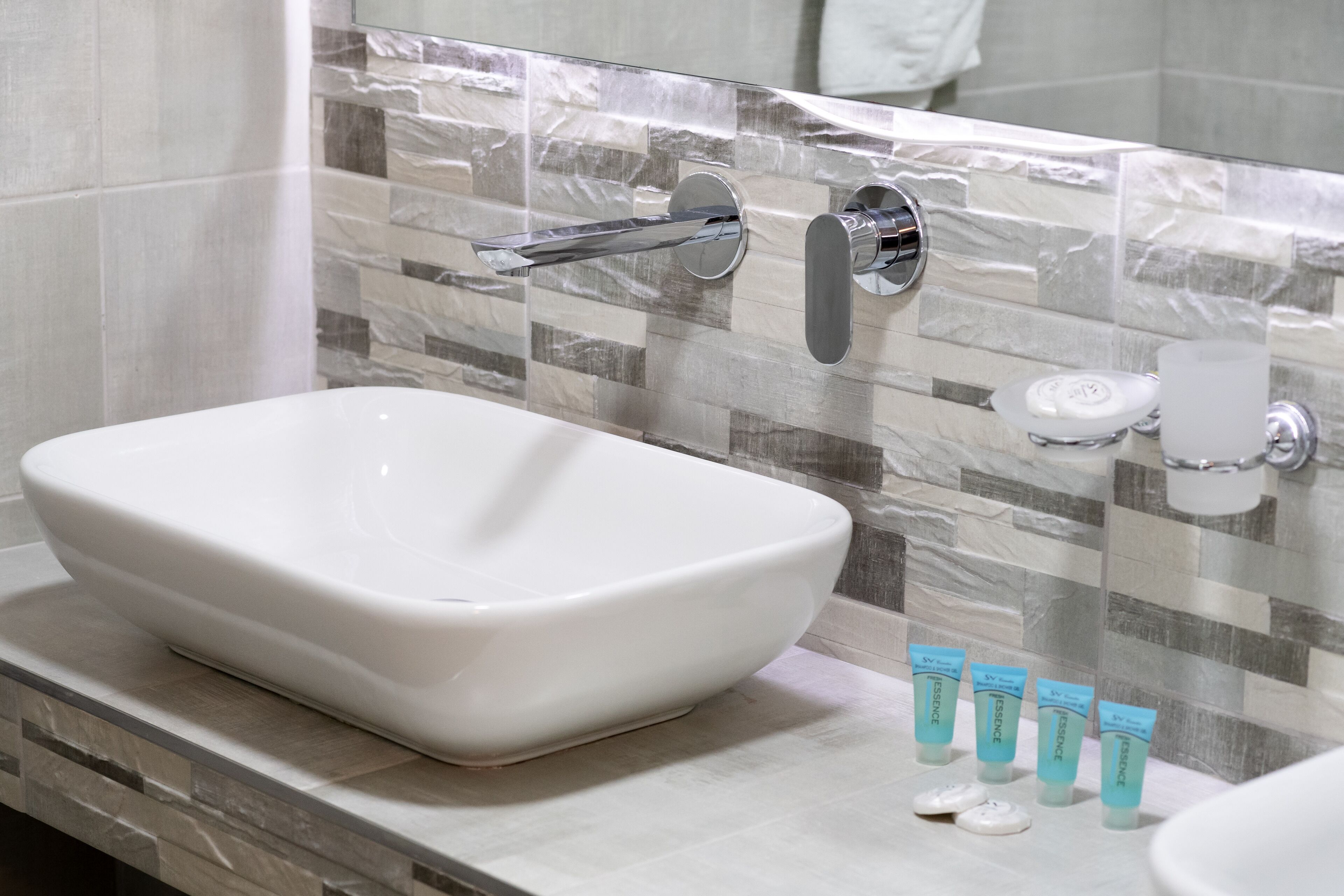 A bathroom with a white vessel sink, a chrome faucet, and a tiled backsplash.