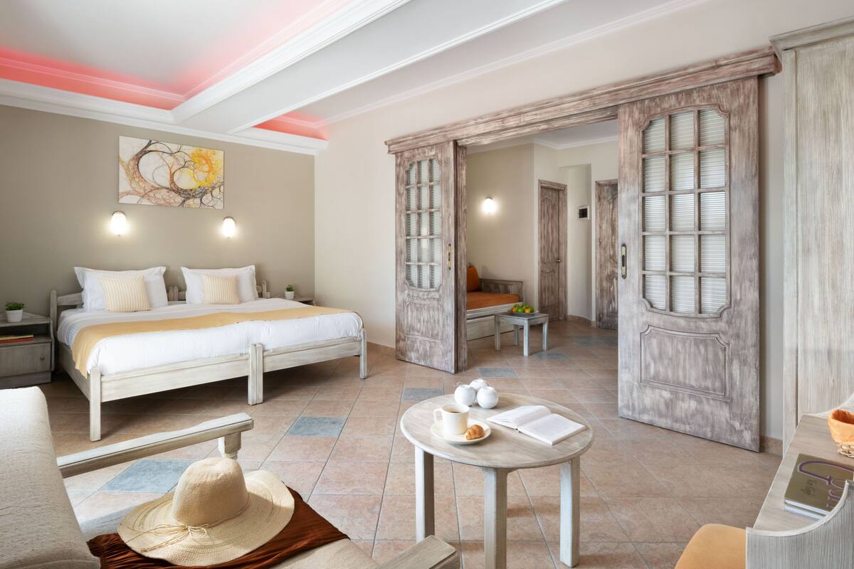 Une chambre d’hôtel comprenant un lit, des tables de chevet, une table à manger et un grand miroir.