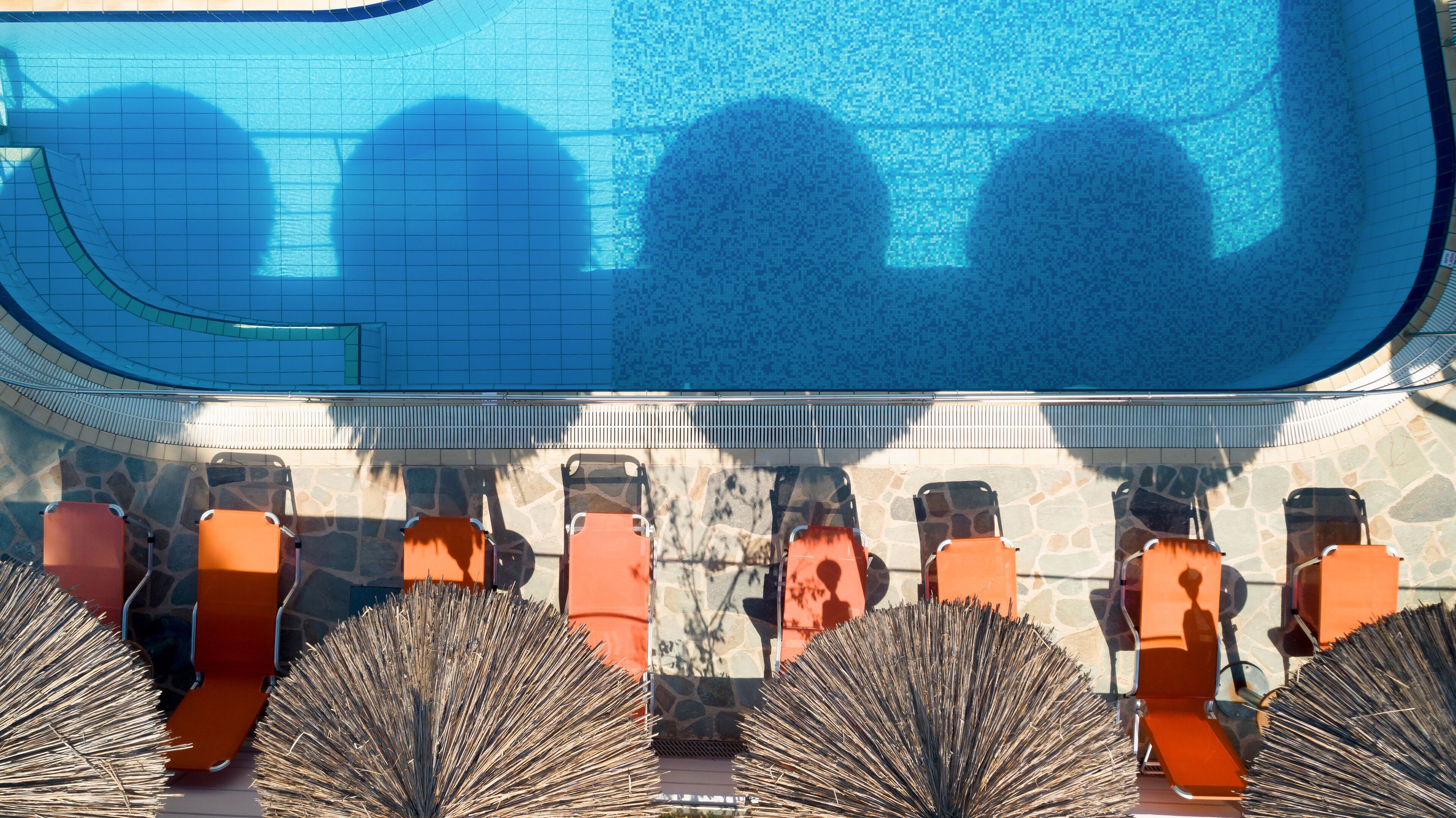 A poolside area with lounge chairs and a stone wall.