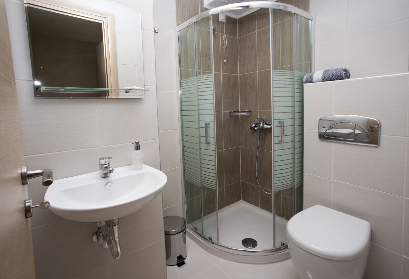 A modern bathroom with a glass-enclosed shower, a white sink, and a toilet.