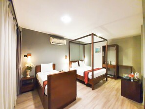 Habitación de hotel con cama con dosel, mesita de noche con lámpara, aire acondicionado y espejo.