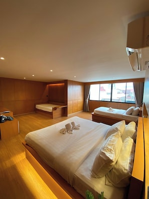 Habitación de hotel con una cama grande, una cama más pequeña, un escritorio y un área de descanso.