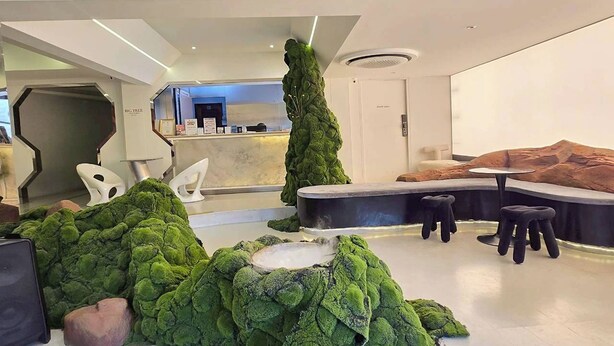 A modern lobby with a reception desk, seating areas, and a unique green moss installation. - Big Tree Old Town Hotel (Chiang Mai)