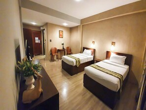 A hotel room with two beds, a desk, a chair, a television, and a small table with a plant. - Big Tree Old Town Hotel (Chiang Mai)