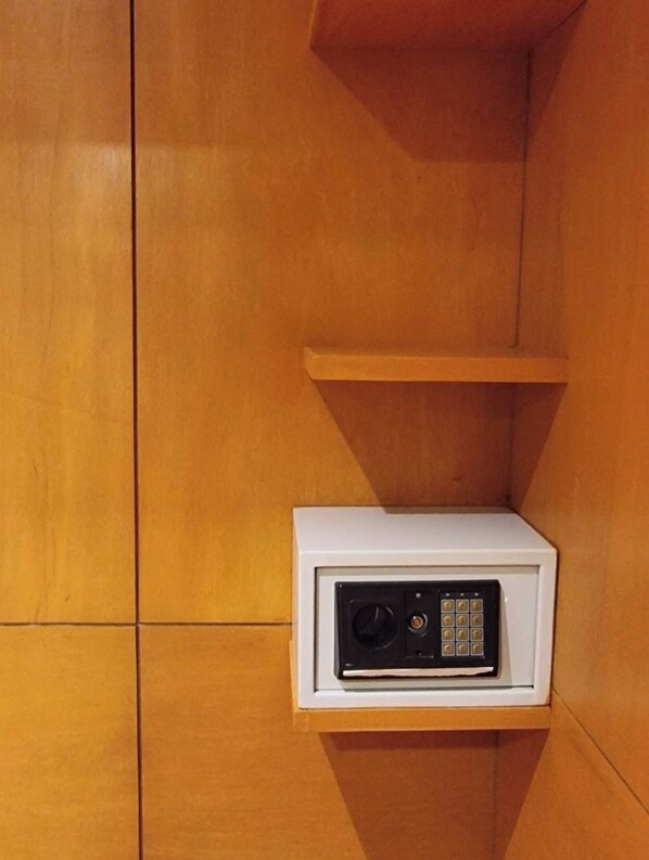 A white electronic device with a keypad and a speaker, mounted on a wooden wall with a shelf above it.