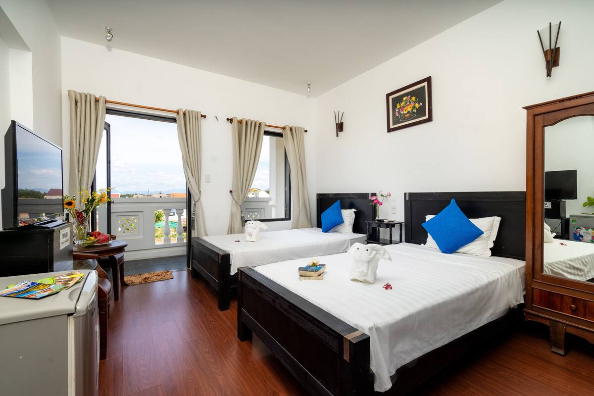 Habitación de hotel con dos camas, televisión, escritorio y vistas a la ciudad.