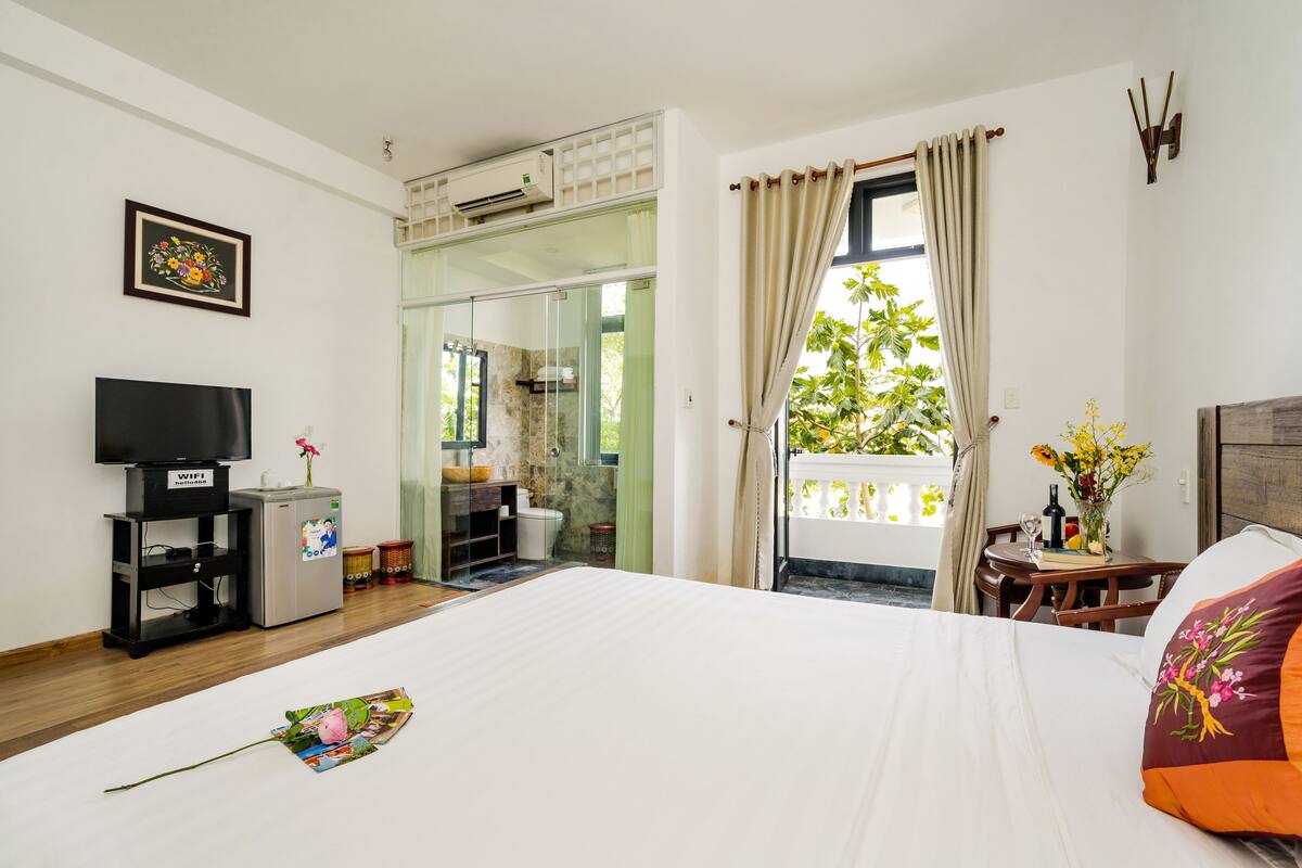 Habitación de hotel con cama, televisión, minibar, baño y balcón con vistas.