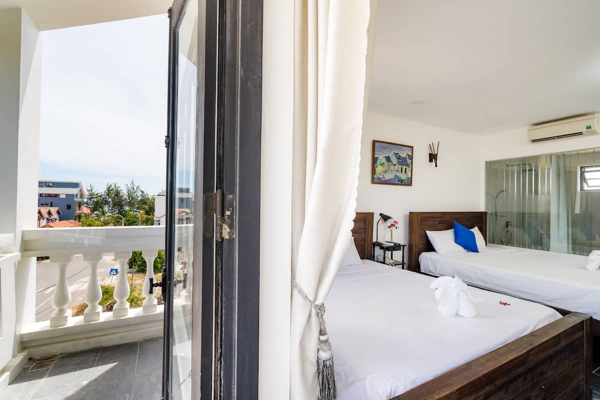 Habitación de hotel con dos camas, un balcón y vista a la ciudad.