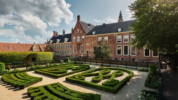 A historic building with a symmetrical garden featuring geometric hedges and a brick facade. - Hotel Prinsenhof (Groningen)
