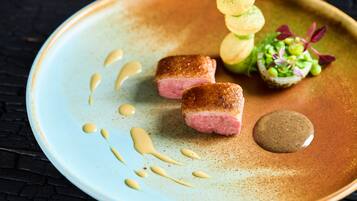 A plate with food items, including two pieces of meat, a dollop of sauce, and a garnish.