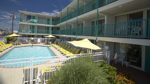 A hotel with a pool area, multiple balconies, and outdoor seating. - The Shangri La Motel (Ocean City)