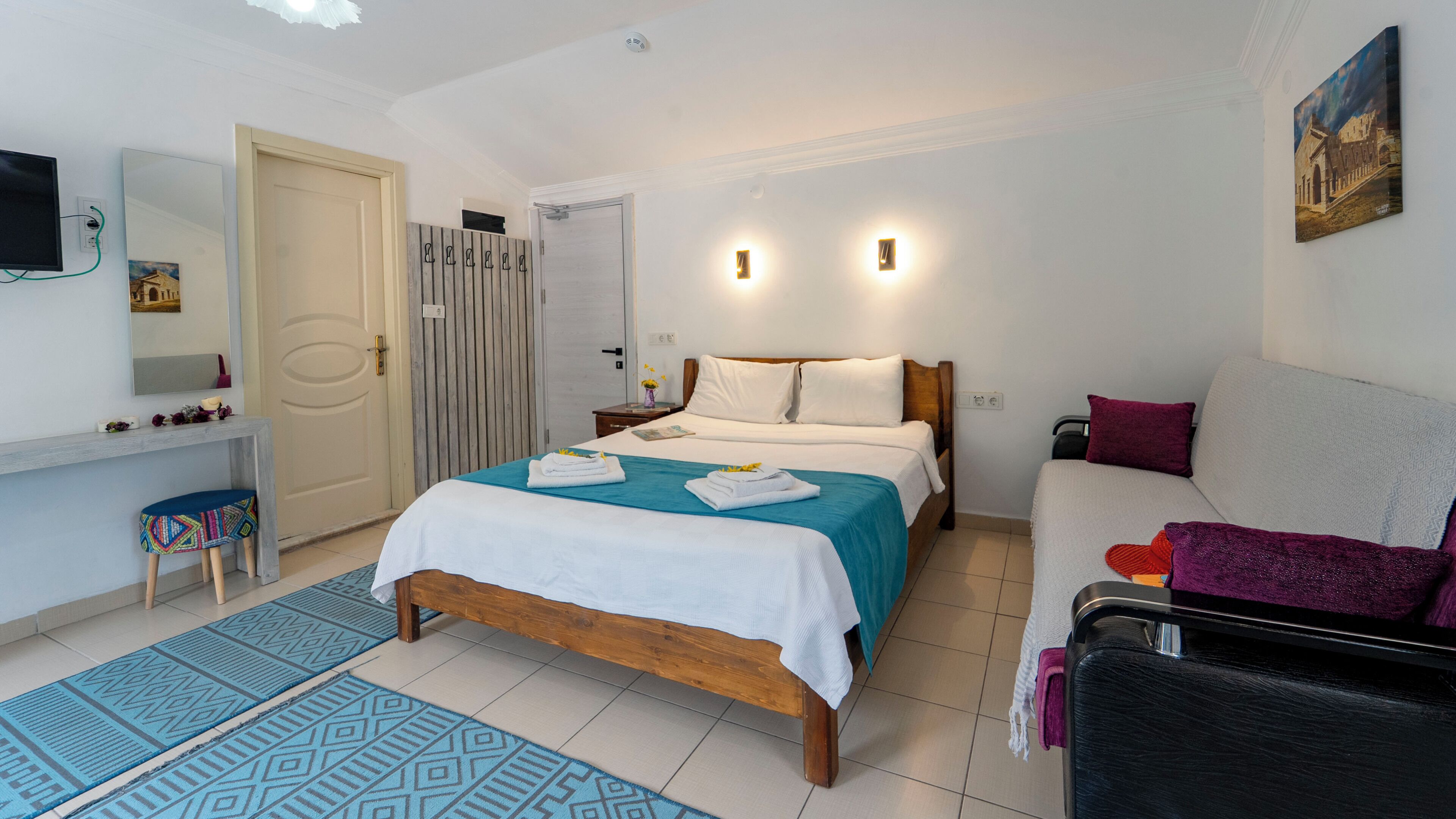 A bedroom with a bed, bedside tables, a desk, a chair, and a painting on the wall.