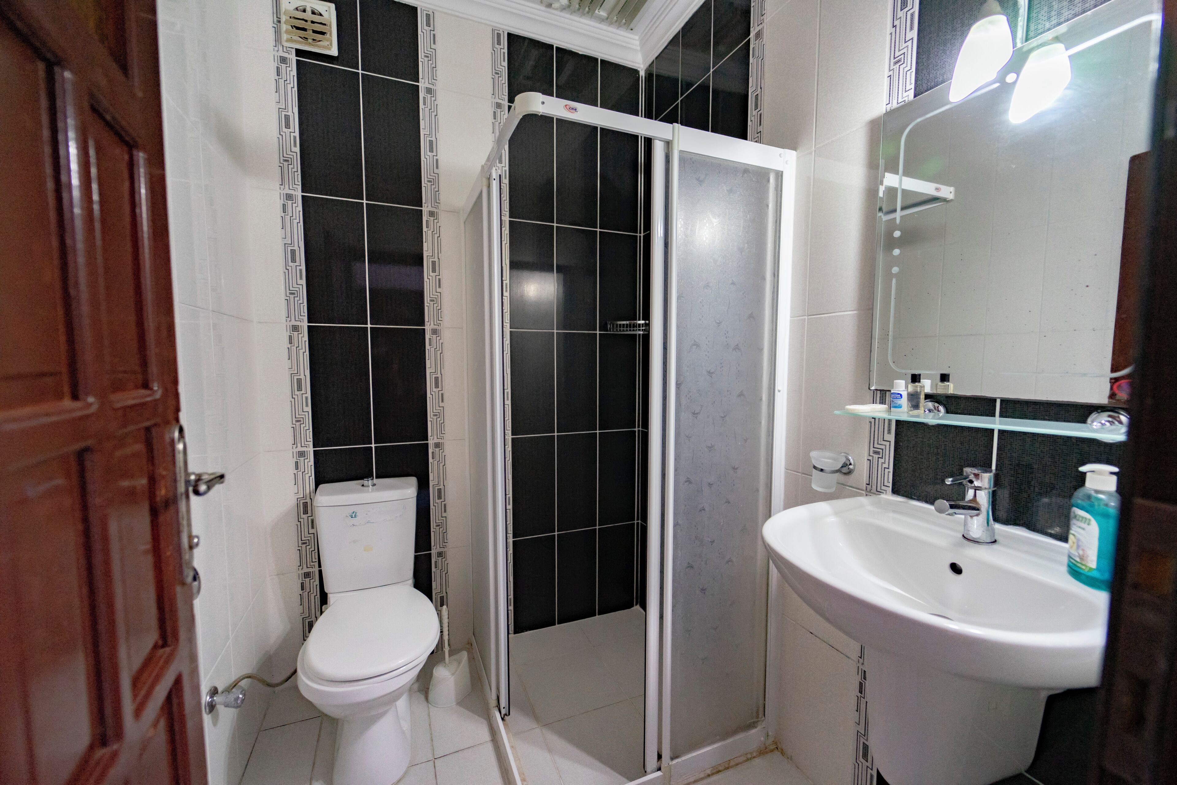 Un baño con inodoro, cabina de ducha y lavabo con espejo.