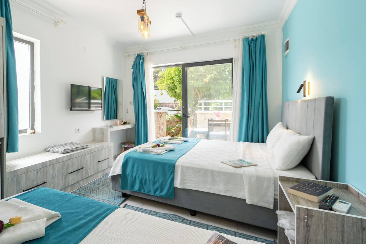 A bedroom with a bed, a TV, a desk, and a window.