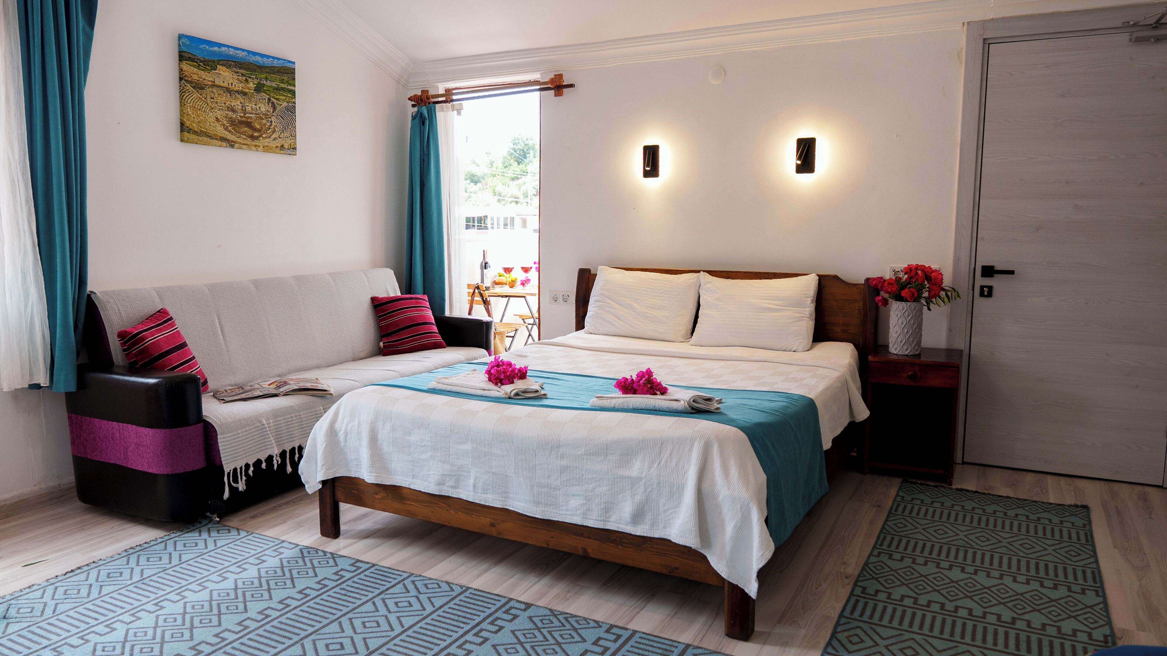 A bedroom with a bed, a sofa, a nightstand, a door, and a window with curtains.