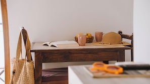 A wooden table with a book, a straw hat, a mug, and a woven bag.