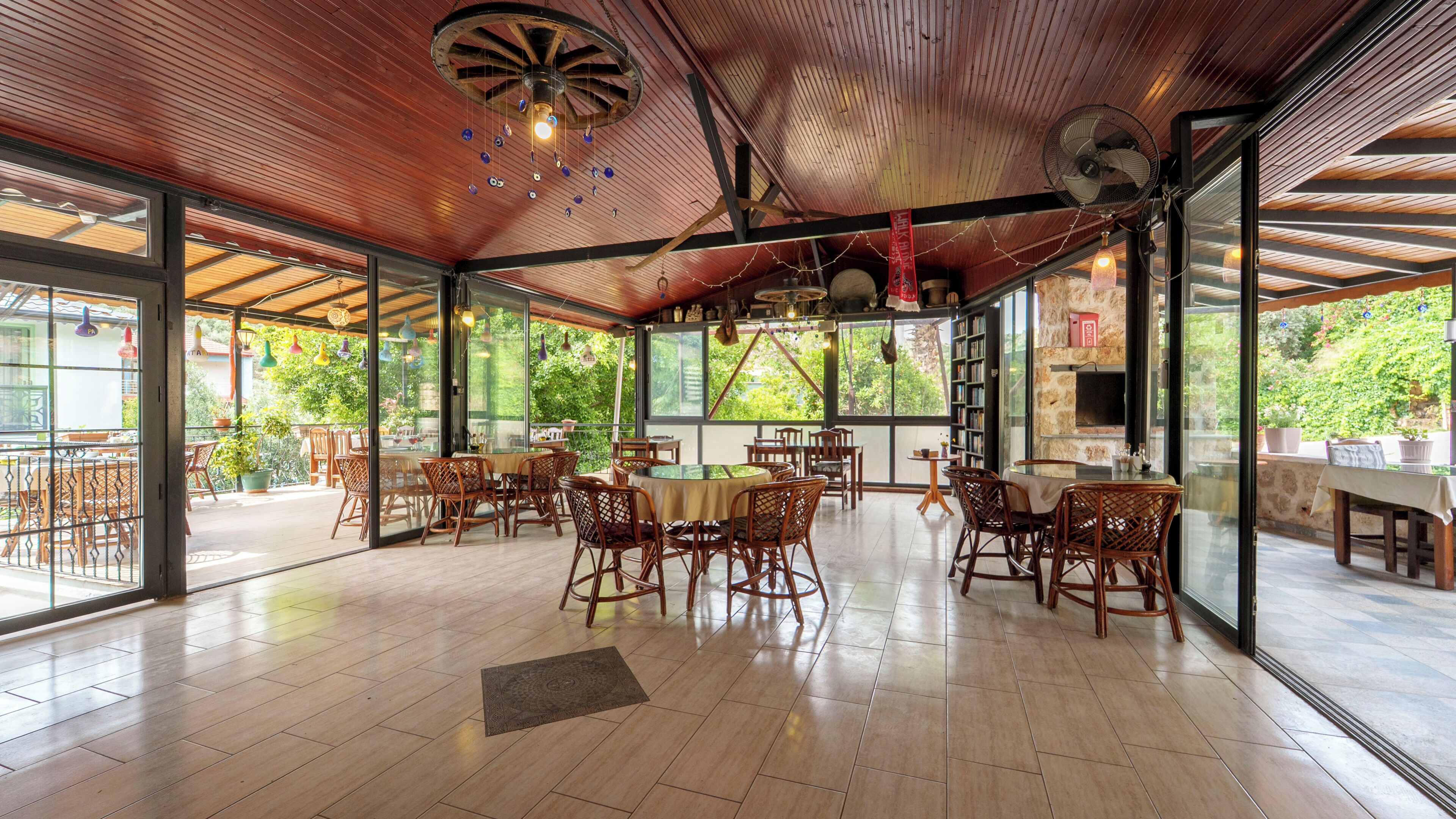 A spacious indoor area with wooden flooring, glass walls, and a ceiling fan.