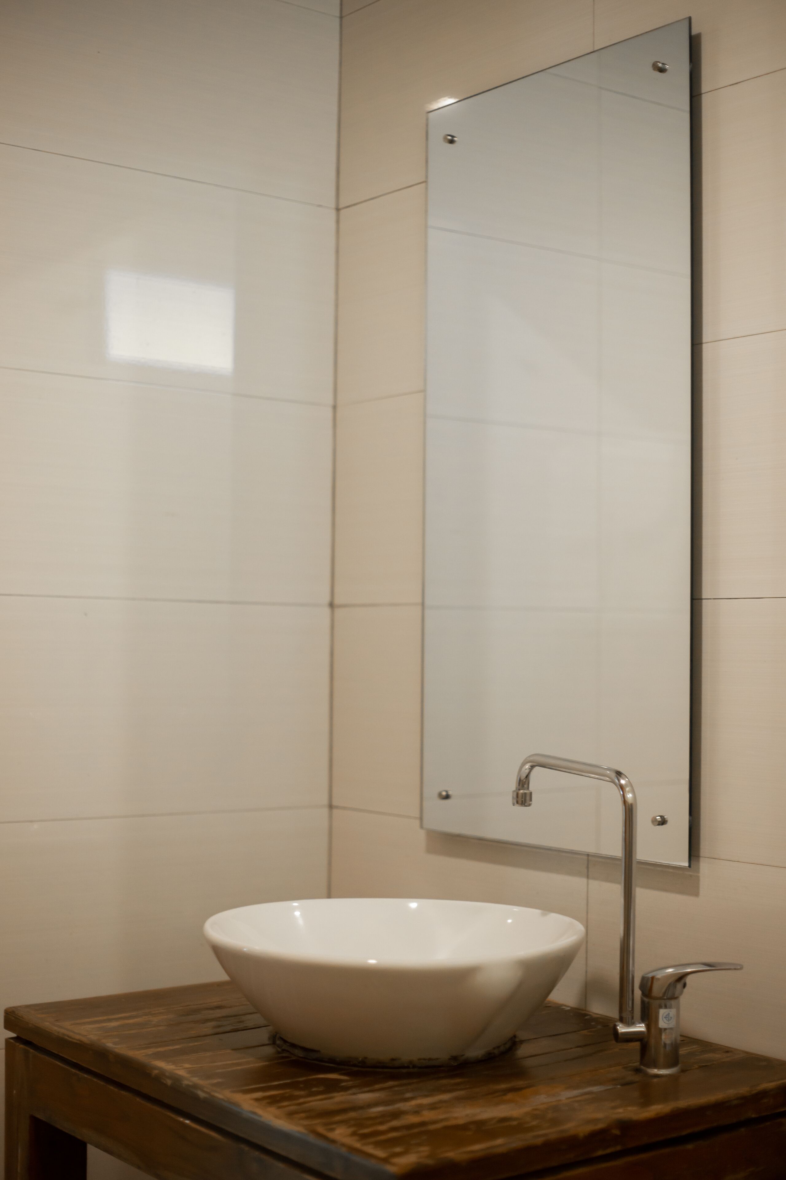 A bathroom with a white vessel sink, a mirror, and a wooden vanity.