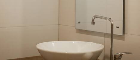 A bathroom with a white vessel sink, a mirror, and a wooden vanity.