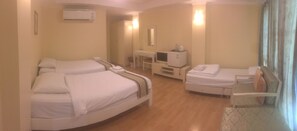 A hotel room with two beds, a desk, a chair, a mirror, and an air conditioning unit.