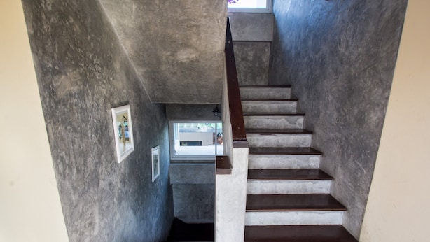 A staircase with a wooden handrail and concrete walls. - Triple Palms House (Chiang Mai)