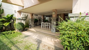 An outdoor patio area with stone pillars, a clock, and a seating arrangement. - Triple Palms House (Chiang Mai)