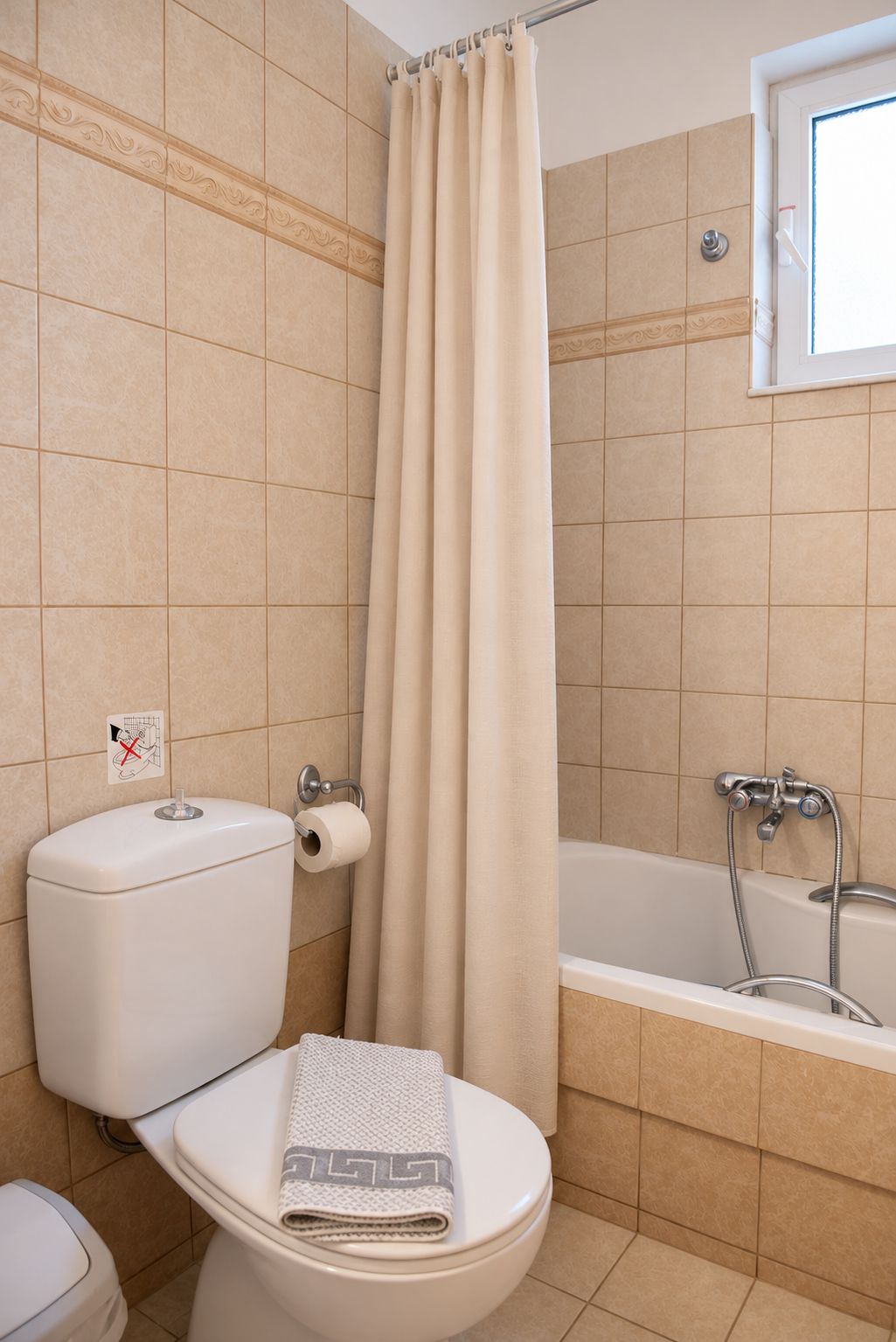 A bathroom with a toilet, a shower curtain, and a bathtub.