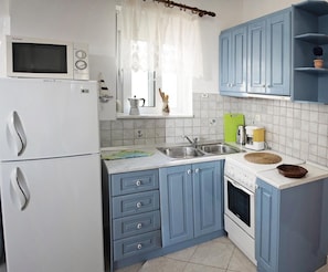 A compact kitchen with a microwave, stove, sink, and blue cabinets. - Nephele Apartments (Rhodes)
