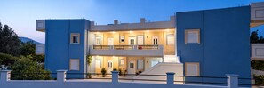 Un edificio moderno a due piani con un balcone, diverse porte e piante in vaso.