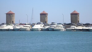 A marina with multiple boats docked and three towers in the background. - Nephele Apartments (Rhodes)